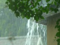 Rain flows from a house roof into a gutter during rain. close-up